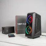 Black speaker with RGB lighting on a table, accompanied by packaging box labeled '1407 RGB' and a remote control.