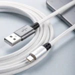 Close-up of a USB and micro USB cable connected to a smartphone, showing braided design and connectors on a light blue surface.