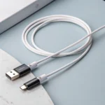 White USB cable with USB and USB-C connectors on a light-colored surface, coiled neatly beside a device edge.